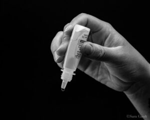 Hand holding an eye drop bottle, ready to use