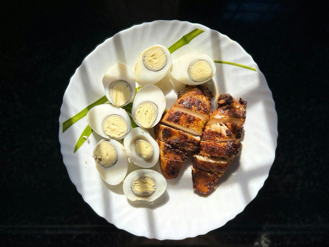 Hard-boiled eggs and sliced seasoned chicken breast on a white plate