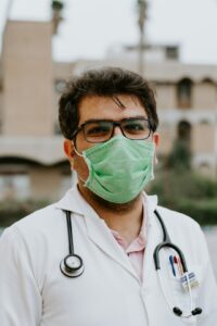 Healthcare worker in a white scrub suit wearing a green face mask