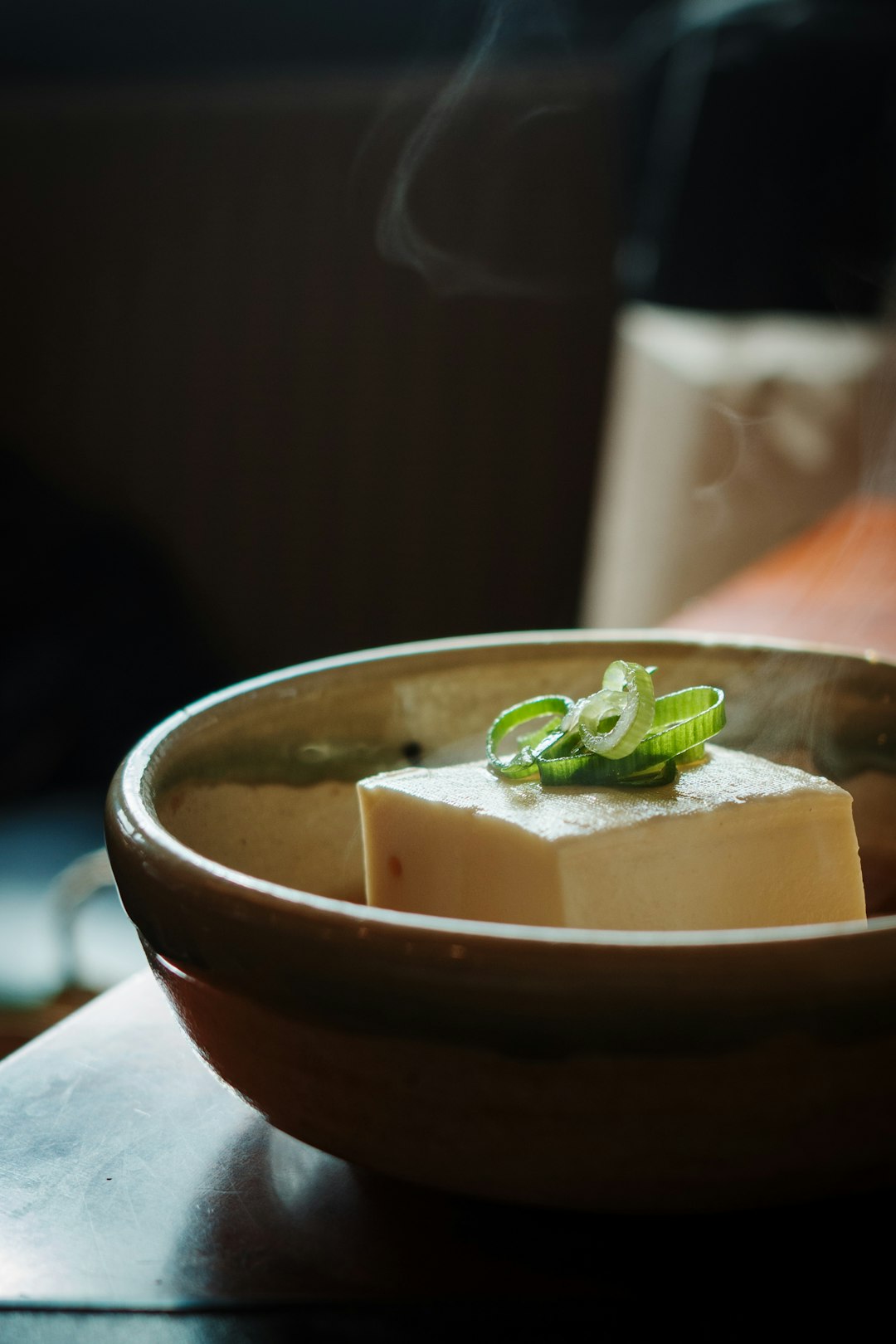 Steaming tofu topped with green onions in a bowl